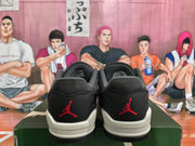 Rear view of black and grey Jordan sneakers with red heel logos and light-colored midsoles.