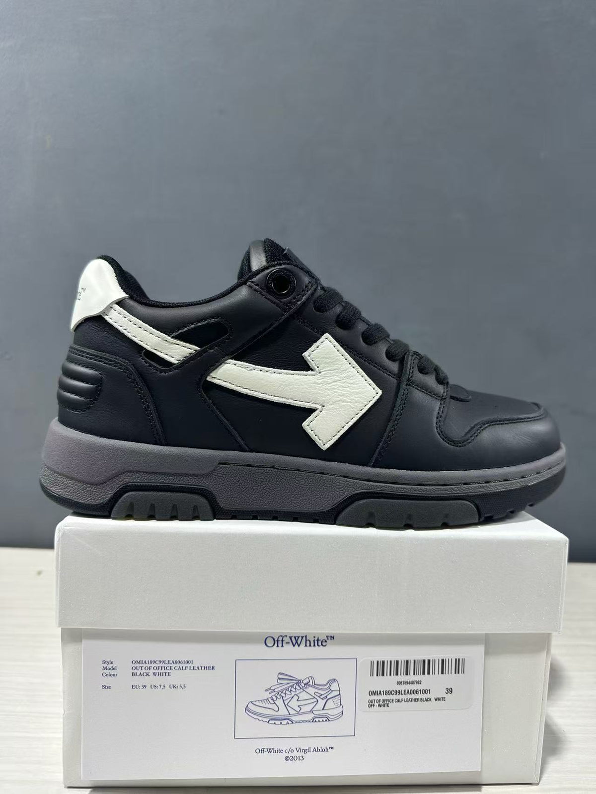 Side view of black and white Off-White Out Of Office sneaker displayed on its labeled box.