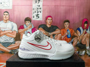 Side view of a white basketball shoe with red Swoosh-style detailing and Kobe-themed graphics
