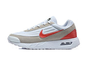 Side view of white Nike Air Max Verse sneakers with taupe overlays, red accents and a visible heel cushioning window.
