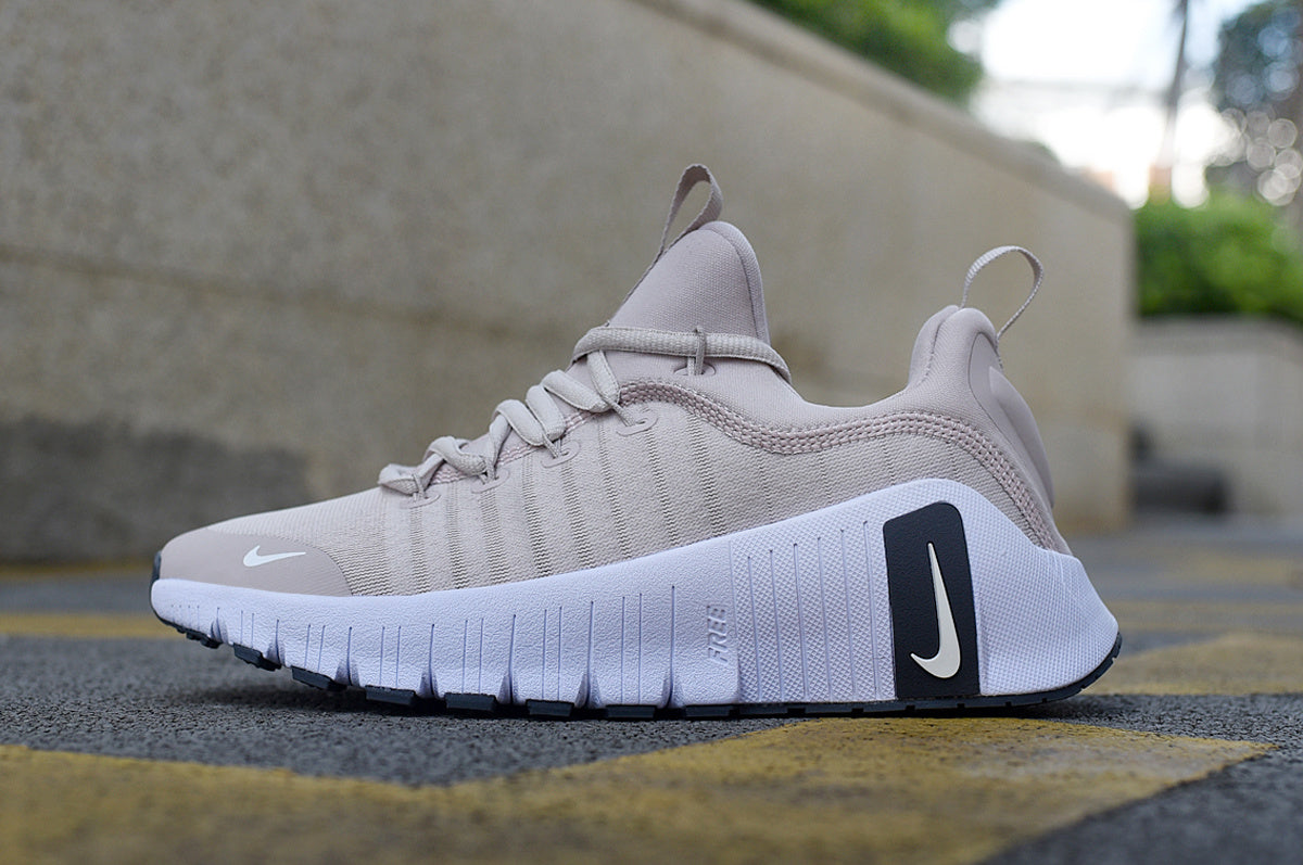 Side view of a light gray Nike sneaker with a white grooved sole and heel pull loop