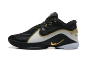 Side profile of a black and white sneaker with gold-trimmed overlays and a visible Nike swoosh.