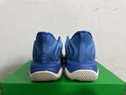 Rear view of blue Nike high-top sneakers with light-colored tread on a green box