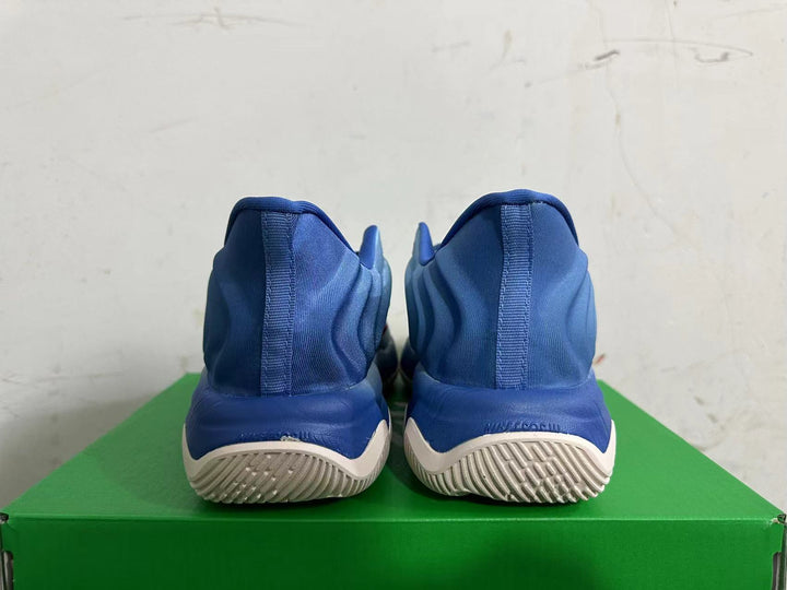 Rear view of blue Nike high-top sneakers with light-colored tread on a green box