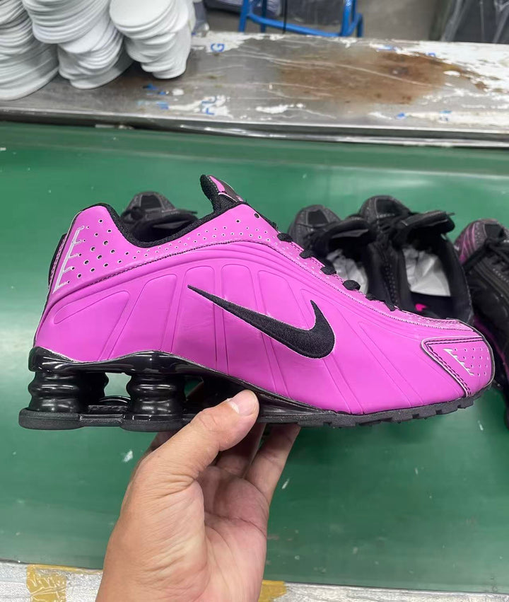 Pink and black Nike Shox-style low-top sneaker with a side Swoosh and visible heel cushioning