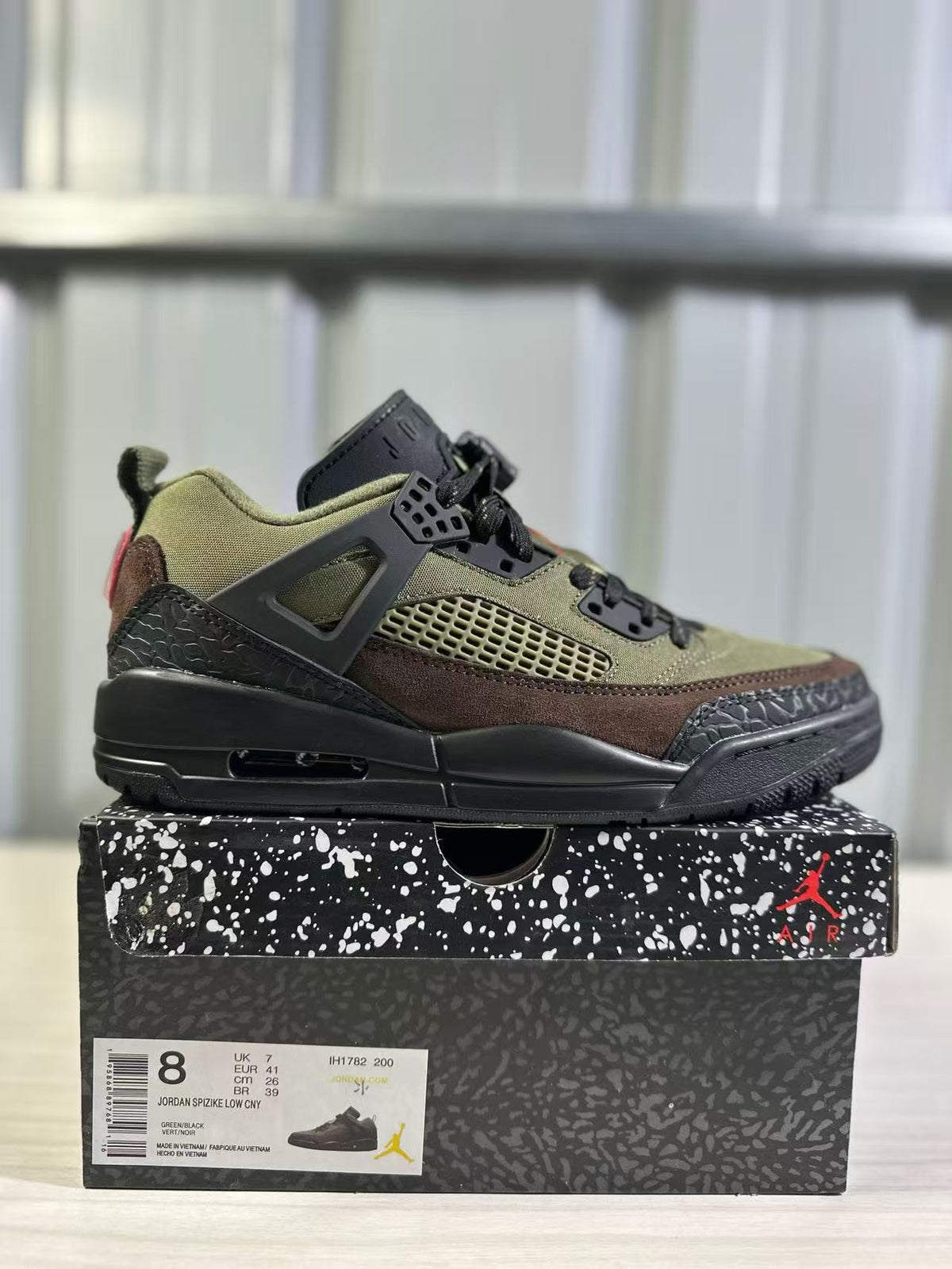 Side view of the green and black Jordan Spizike Low sneaker displayed on its patterned box, with the box label visible.