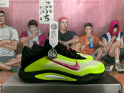 Side profile of a green and black Nike basketball sneaker with a pink swoosh and layered midsole detailing.