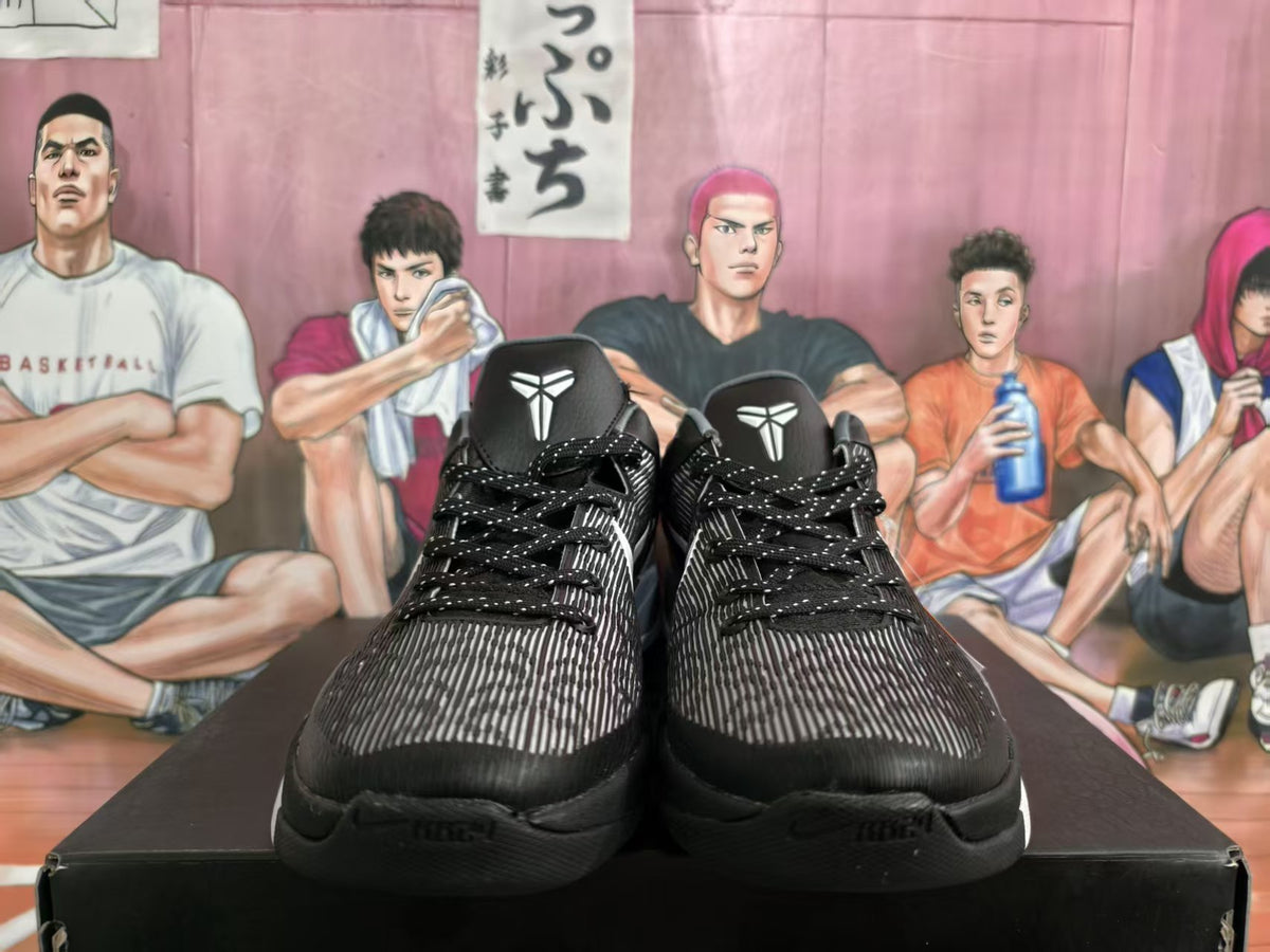 Pair of black and gray basketball sneakers shown from the front with patterned uppers, black laces, white tongue emblems, and a basketball-themed backdrop.