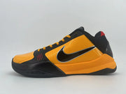 Side profile of the orange-and-black shoe with a yellow-orange lacing system and black outsole.