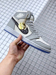 Full side profile showing the gray and white upper, patterned Swoosh, gold charm, and blue outsole.