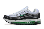 Side view of white, black, and green Nike sneakers with layered detailing and green sole accents.