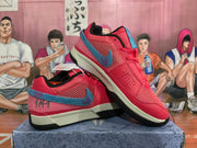 Angled view of two red Nike sneakers displaying mesh panels, blue accents, cream midsoles, and black rubber outsoles.