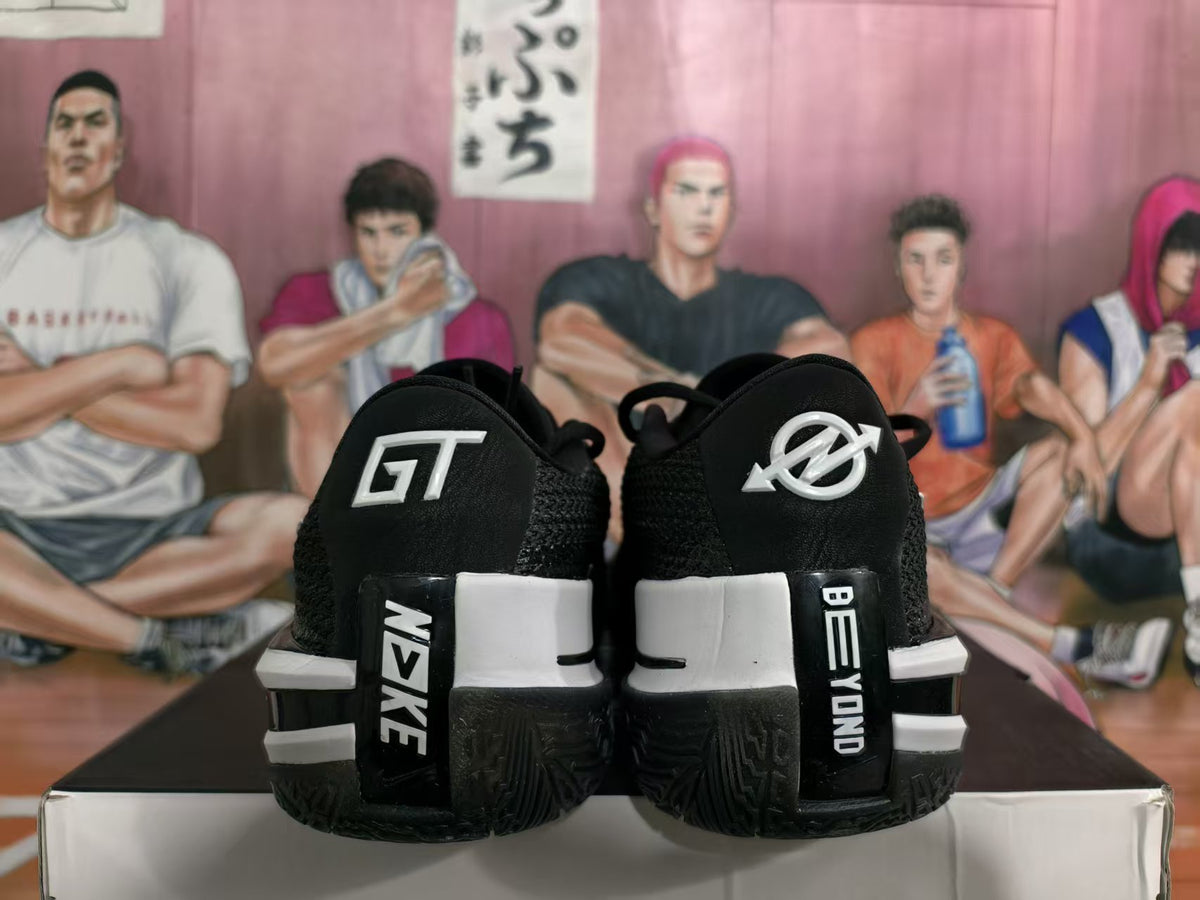 Rear view of black and white Nike basketball sneakers showing GT heel branding, contrasting heel panels, and textured outsoles.