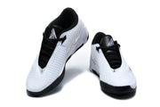 Pair of white low-top basketball shoes with black laces and red and black side accents