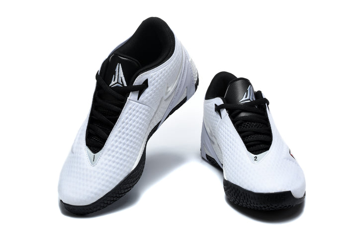 Pair of white low-top basketball shoes with black laces and red and black side accents