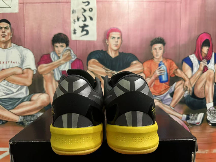 Rear view of black and yellow Nike Kobe basketball shoes showing patterned heel panels and yellow soles.