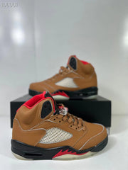 Close angled view of the brown high-top sneaker with red lining, laces, and contrasting side panel.