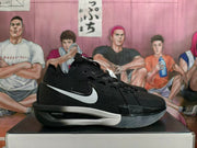 Side view of a black Nike basketball shoe with a white Swoosh and translucent outsole.