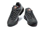 Front view of a pair of grey Nike Air Max 95 TT sneakers with orange tongue details