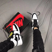 Top-down view of the pair worn with black jeans beside the shoebox.