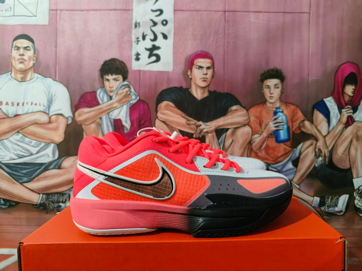 Side view of red and gray Nike basketball sneakers displayed on an orange shoebox.