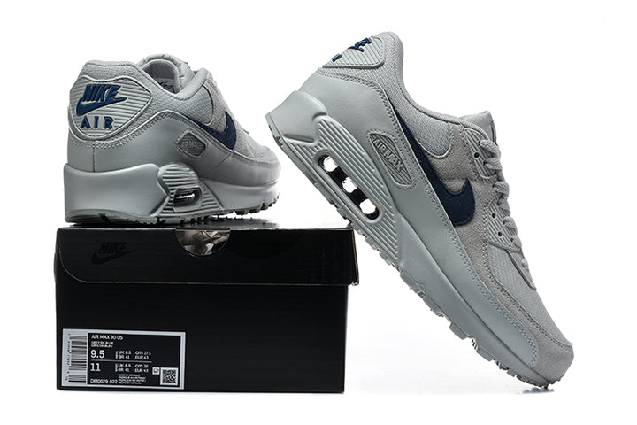Grey and navy Nike Air Max 90 sneakers displayed with a shoe box; the box label shows a sample size.