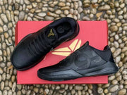 Top and side view of the black sneakers arranged on a red box, showing tonal side panels and logos.