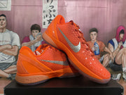 Angled view of the orange Nike sneakers displaying the textured upper, silver Swoosh, padded collar, and outsole.