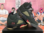 Angled view of a pair of black high-top sneakers highlighting the side panels, red accents, number 23 detail, and outsole.