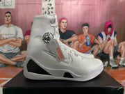 Side view of a white high-top basketball shoe with a Nike Swoosh and dark midsole panel