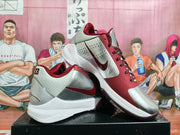 Angled view of the pair showing the burgundy and silver upper, side Swoosh, and white midsole.