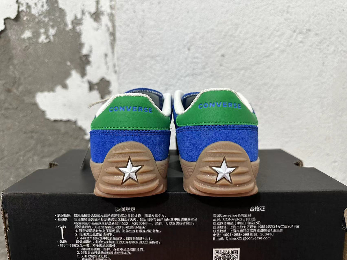 Rear view of blue Converse shoes with green heel panels, white star heel details, and gum-colored soles