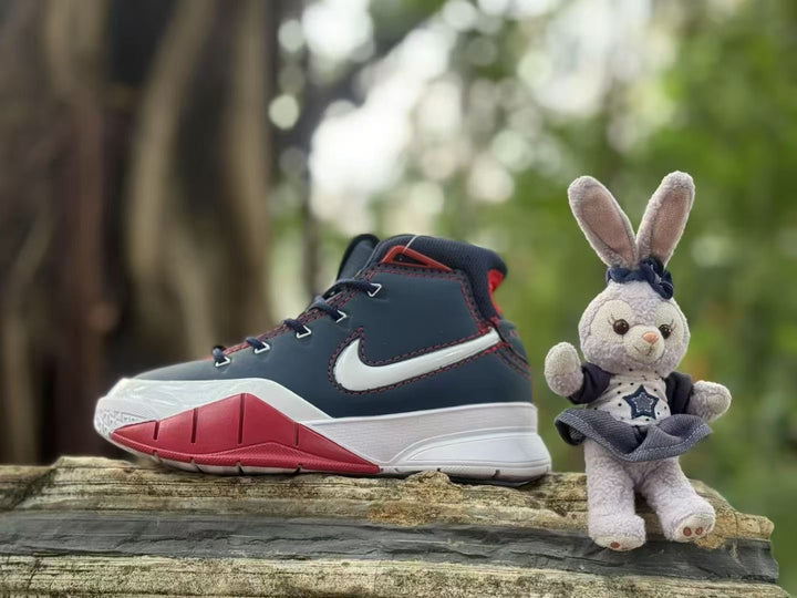 Side view of a navy, white, and red kids' high-top sneaker beside a plush rabbit outdoors.