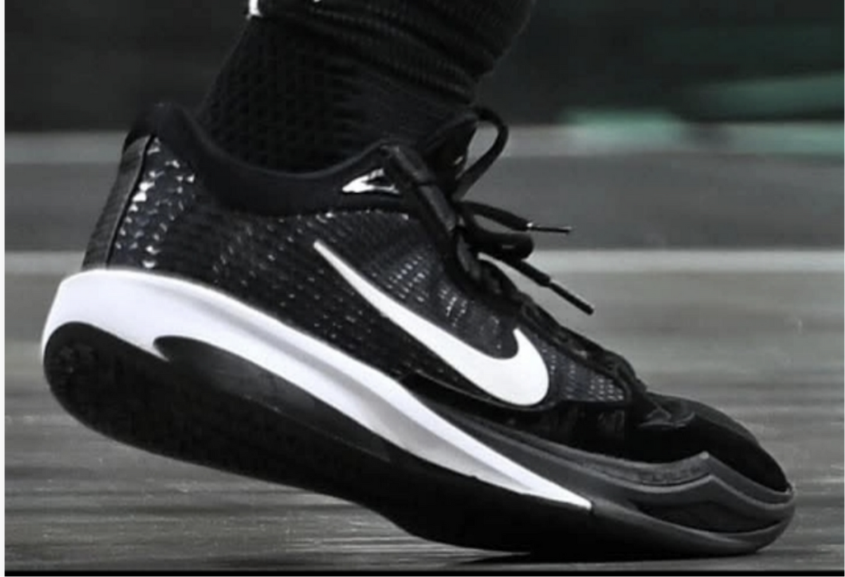Black Nike sneaker with a white Swoosh, black laces, textured upper, and black-and-white sole.
