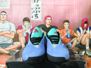 Pair of Nike basketball shoes shown from the front, with aqua tongues, blue uppers, red logos and black outsoles.