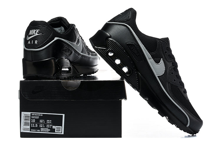 Black and silver Nike Air Max 90 sneakers beside a shoebox; the box label shows a sample size.
