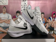 Angled view of the white and black Nike basketball sneakers, showing the swoosh, lace system, patterned forefoot overlay and rubber outsole.