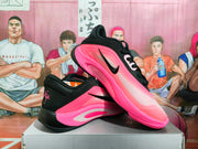 Angled view of pink and black Nike basketball sneakers displaying the side panels, black collars, laces, and outsoles.