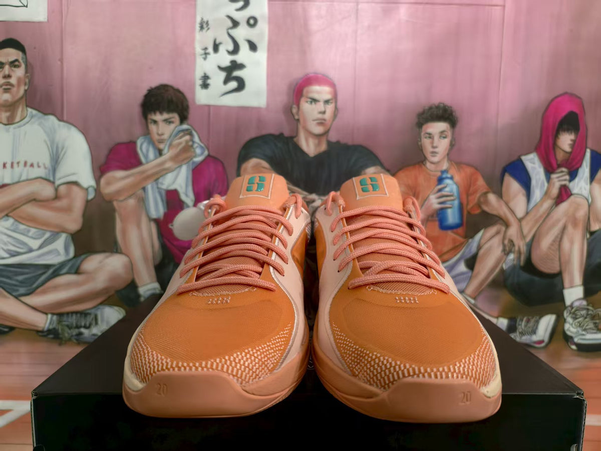 Front view of orange Nike sneakers with pink laces, contrasting toe details, and a basketball-themed illustrated backdrop.