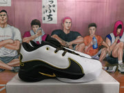 Side view of a black-and-white basketball sneaker showing layered panels, gold trim, a gold Swoosh, and a contrasting rubber outsole.