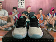Front view of cream Nike sneakers with black laces, black tongues and teal-blue outsole details.