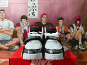 Front view of white, black, and red high-top basketball shoes with midfoot straps.