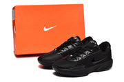 Black sneaker pair displayed beside an orange Nike-marked shoe box.