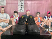 Front view of black Nike basketball sneakers with textured uppers, black laces, and yellow tongue branding.