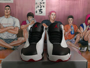 Front view of black and white high-top sneakers with black laces, white side panels and red Jordan tongue logos.