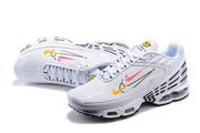 Pair of white Nike Air Max Plus sneakers with pink and yellow side graphics.