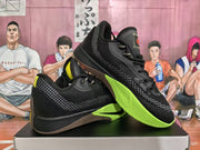 Angled view showing the black textured upper, gray side pattern, bright green outsole, and contrasting brown outsole section.