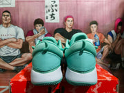 Rear view of the pale green basketball sneakers showing padded collars, heel panels, white midsoles, and textured outsoles.