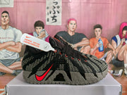 Side view of a black and grey Nike basketball shoe with red Swoosh accents and textured grey outsole