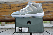 Side view of a gray and white sneaker on a dark box outdoors, with the box label visible.
